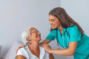 Older adult choosing clothing while a caregiver offers respectful assistance in a bright private room.